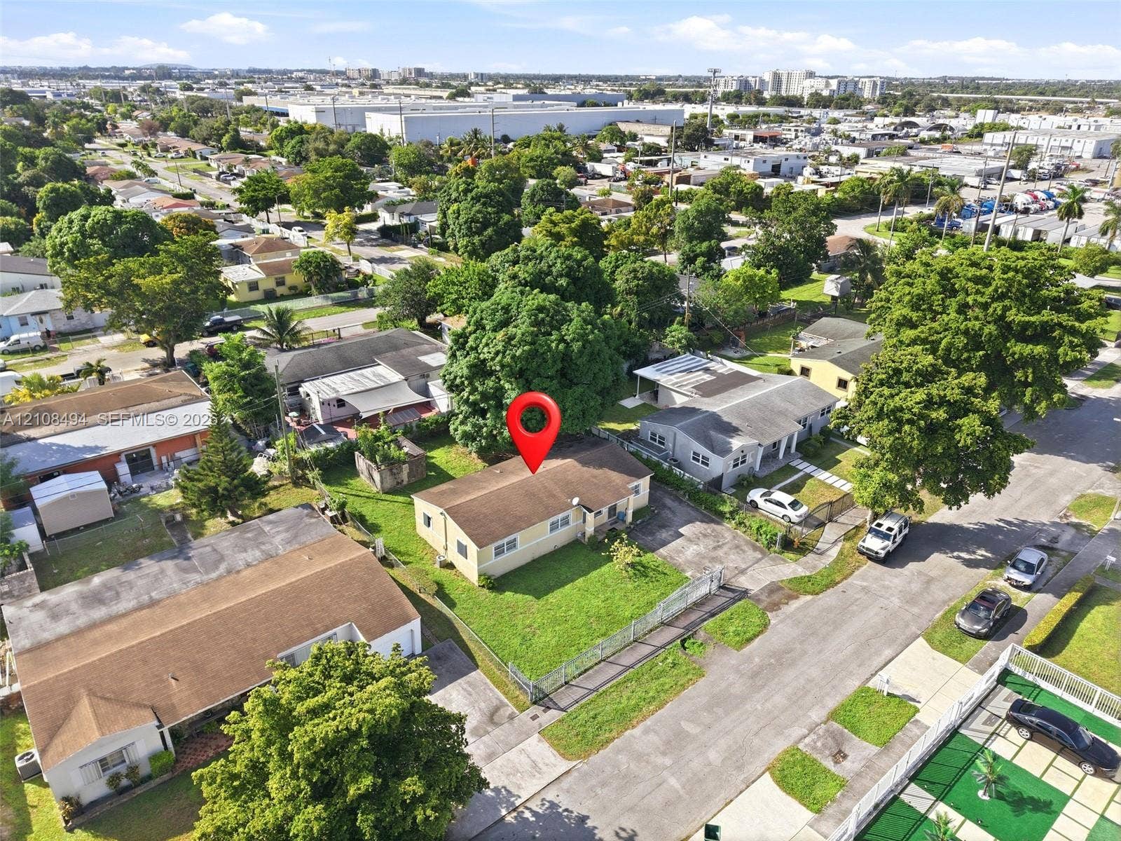 6940 NW 28th Avenue, Miami, FL 33147 Aerial perspective of a single-story residence featuring a shingled roof, exterior siding, and a front lawn enclosed by perimeter fencing