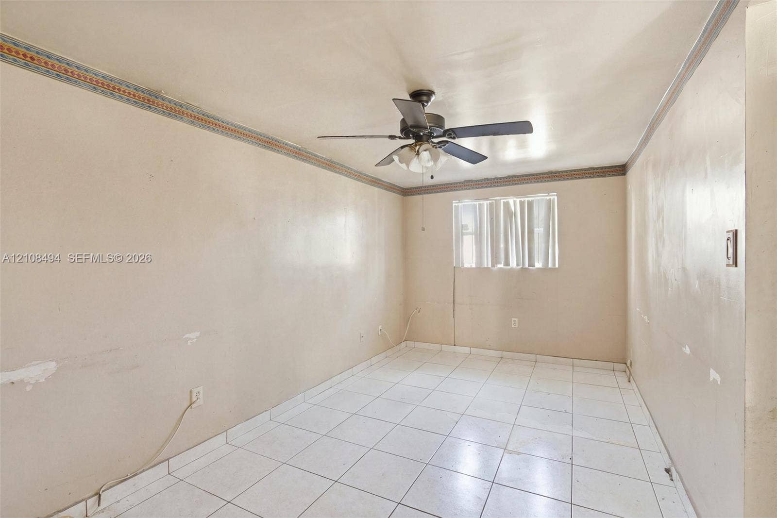 6940 NW 28th Avenue, Miami, FL 33147 Interior room featuring light-toned tile flooring, decorative crown molding, and a central ceiling fan with an integrated light fixture