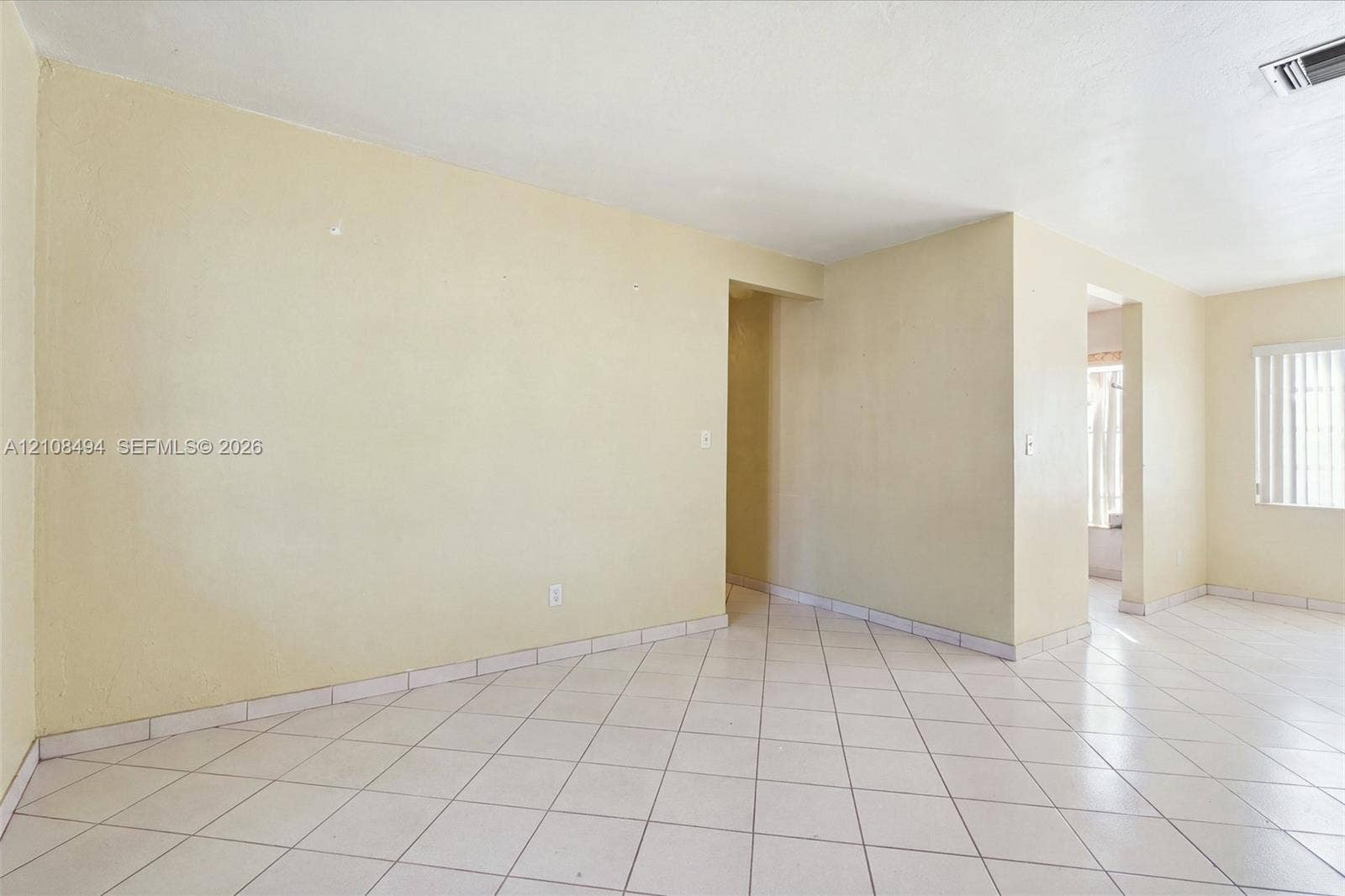 6940 NW 28th Avenue, Miami, FL 33147 Interior space featuring neutral-toned walls, tile flooring set on a diagonal pattern, and vertical slat window blinds