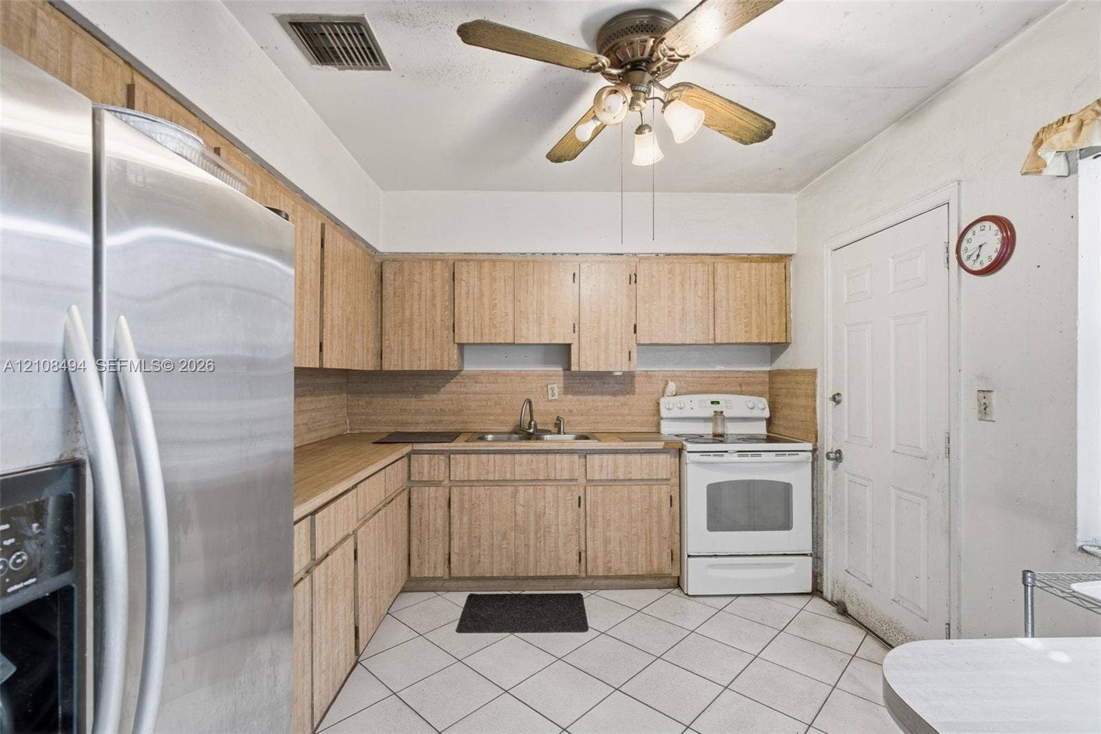 6940 NW 28th Avenue, Miami, FL 33147 Kitchen featuring wood-finish cabinetry, stainless steel refrigerator, white free-standing range, double-basin sink, and tile flooring