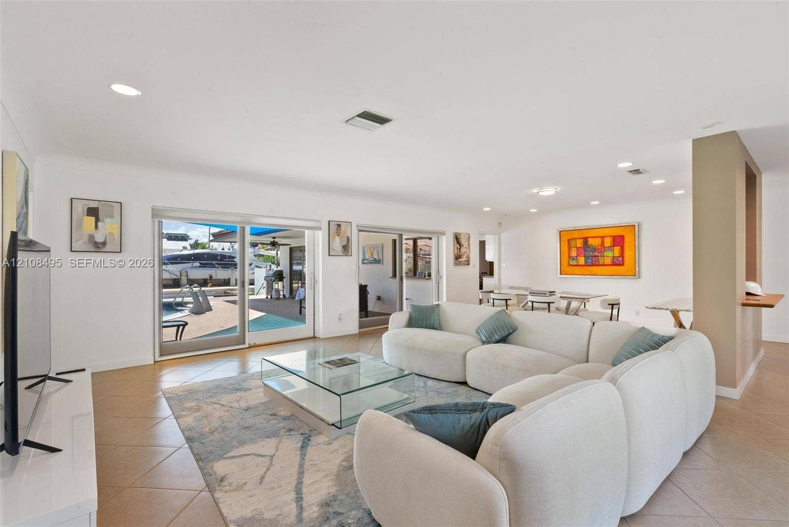 3080 NE 43rd Street, Fort Lauderdale, FL 33308 Open-concept living space featuring neutral tile flooring, recessed ceiling lighting, and expansive dual sliding glass doors