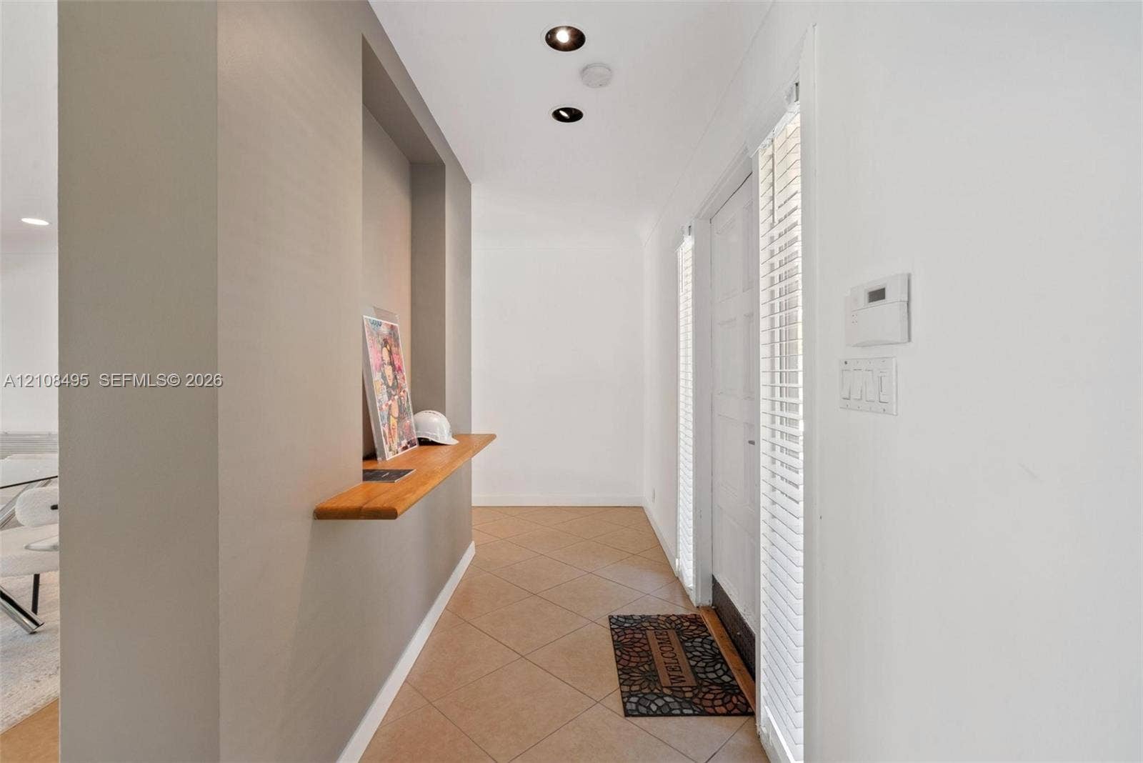 3080 NE 43rd Street, Fort Lauderdale, FL 33308 Entryway featuring a built-in wood-finish display shelf, recessed ceiling lighting, tile flooring, and vertical blinds