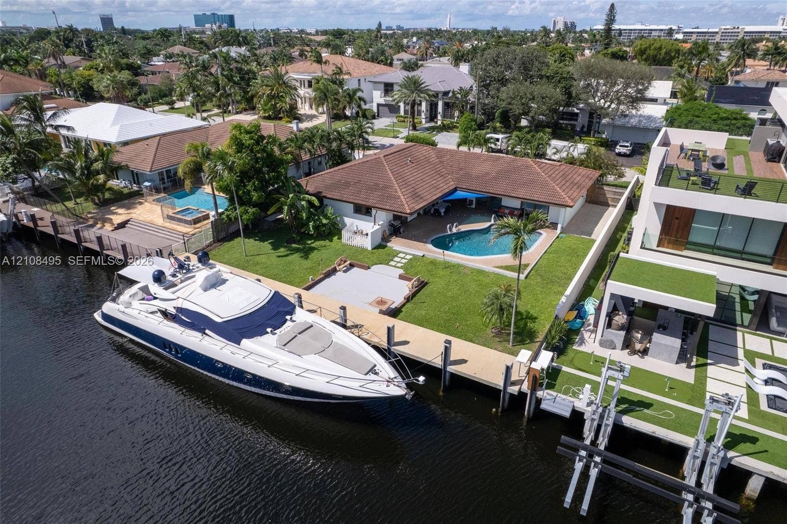 3080 NE 43rd Street, Fort Lauderdale, FL 33308 Waterfront property featuring a private boat dock, swimming pool, manicured lawn, and hardscaped patio area