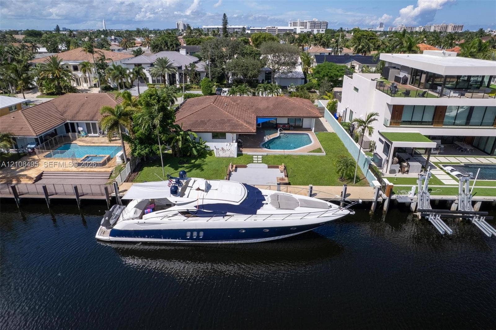 3080 NE 43rd Street, Fort Lauderdale, FL 33308 Waterfront property featuring a private boat dock, concrete seawall, in-ground swimming pool, and manicured lawn