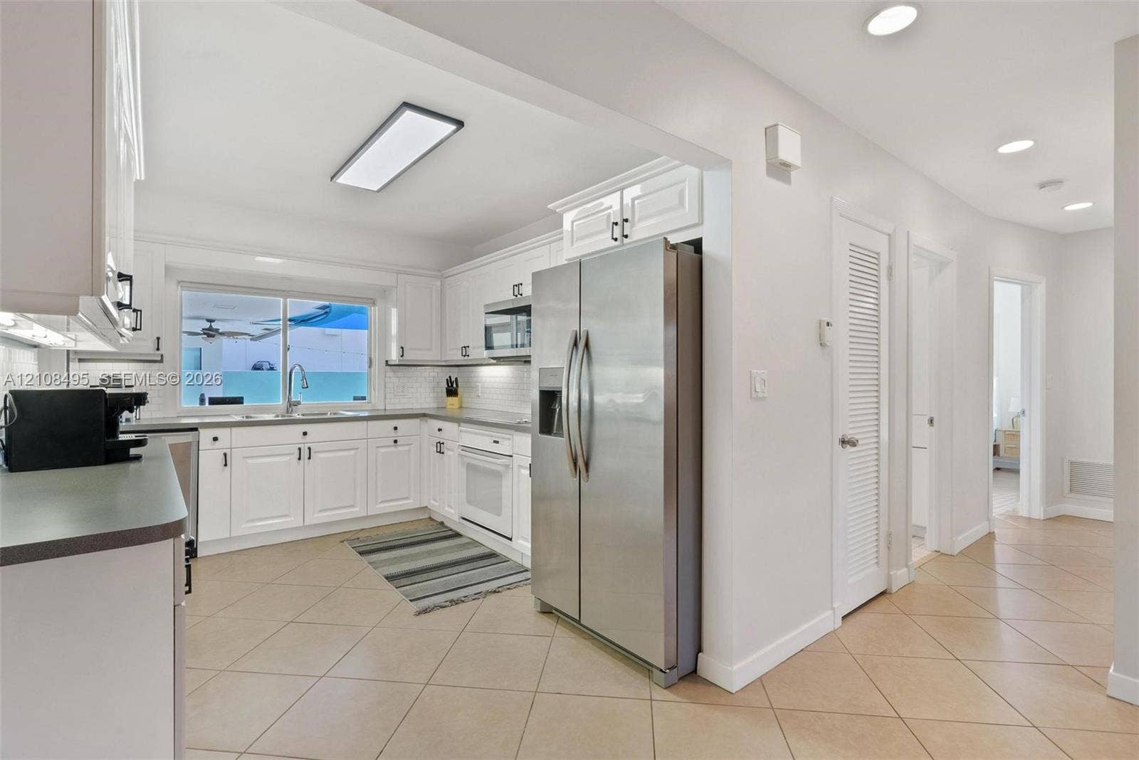 3080 NE 43rd Street, Fort Lauderdale, FL 33308 Kitchen featuring white cabinetry, stainless steel side-by-side refrigerator, built-in microwave, tile flooring, and recessed lighting