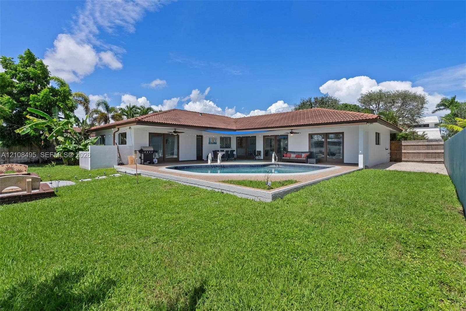 3080 NE 43rd Street, Fort Lauderdale, FL 33308 Backyard featuring an in-ground swimming pool, concrete patio, tiled roof, and perimeter fencing