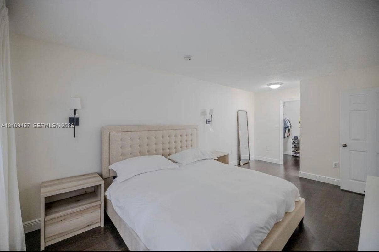 6245 SW 47th Manor, #101, Davie, FL 33314 Bedroom interior featuring dark wood-finish flooring, recessed ceiling lighting, wall-mounted light fixtures, and a white six-panel interior door