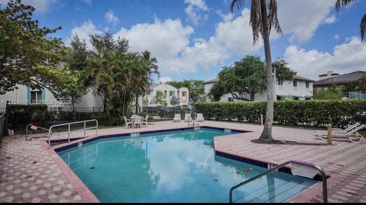 6245 SW 47th Manor, #101, Davie, FL 33314 Swimming pool with a paved deck, perimeter hedging, and metal fencing