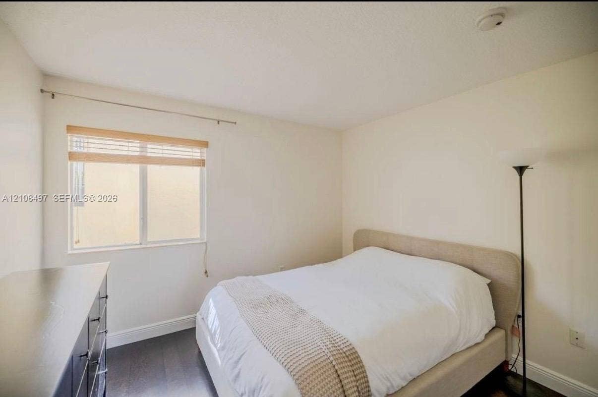 6245 SW 47th Manor, #101, Davie, FL 33314 Room featuring dark wood-finish flooring, neutral wall tones, and a single-pane sliding window with horizontal slat blinds