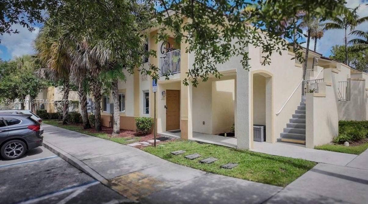 6245 SW 47th Manor, #101, Davie, FL 33314 Stucco exterior featuring a second-story balcony with metal railings and an external concrete staircase