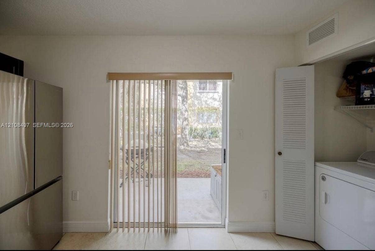 6245 SW 47th Manor, #101, Davie, FL 33314 Sliding glass door with vertical blinds, stainless steel refrigerator, louvered closet door, and tile flooring