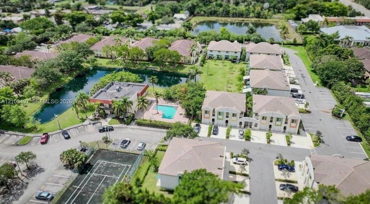 6245 SW 47th Manor, #101, Davie, FL 33314 Aerial view featuring a paved tennis court, outdoor swimming pool, water feature, and off-street parking area