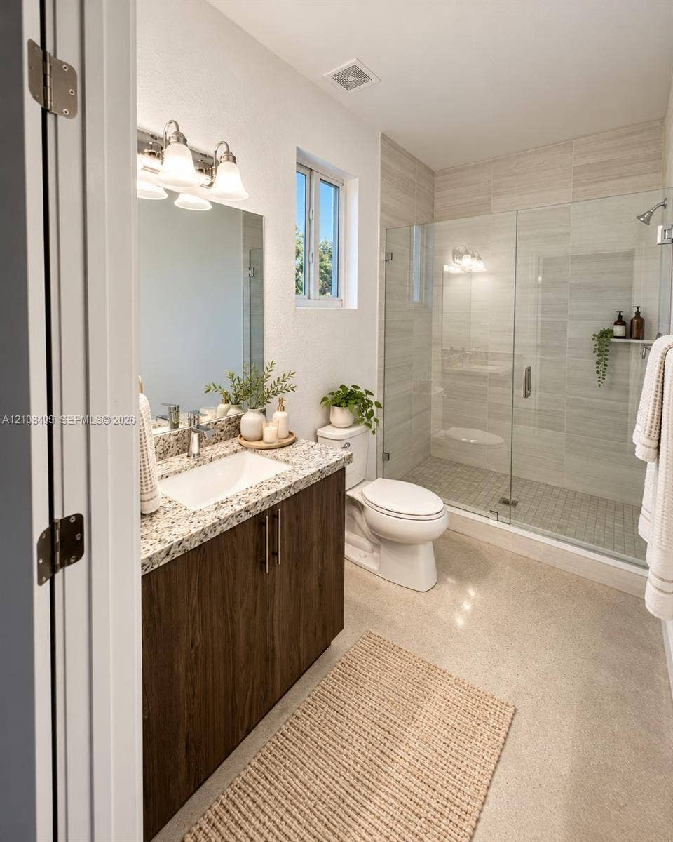 104 NW 31st Avenue, Fort Lauderdale, FL 33311 Bathroom featuring a vanity with wood-finish cabinetry, stone countertop, integrated sink, and glass-enclosed shower with tiled surround
