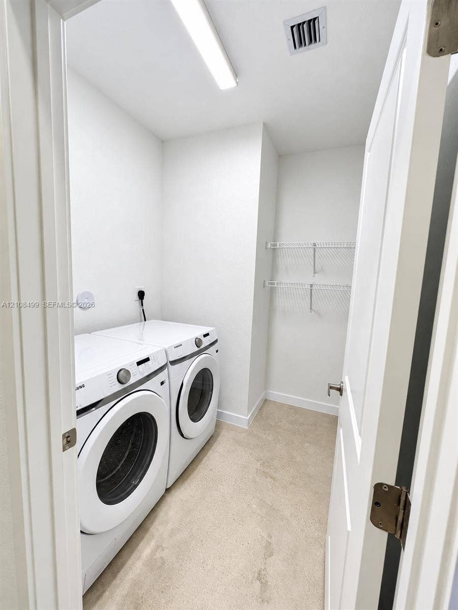 104 NW 31st Avenue, Fort Lauderdale, FL 33311 Utility space featuring neutral carpeting, white walls, overhead LED lighting, and dual wall-mounted wire storage shelves