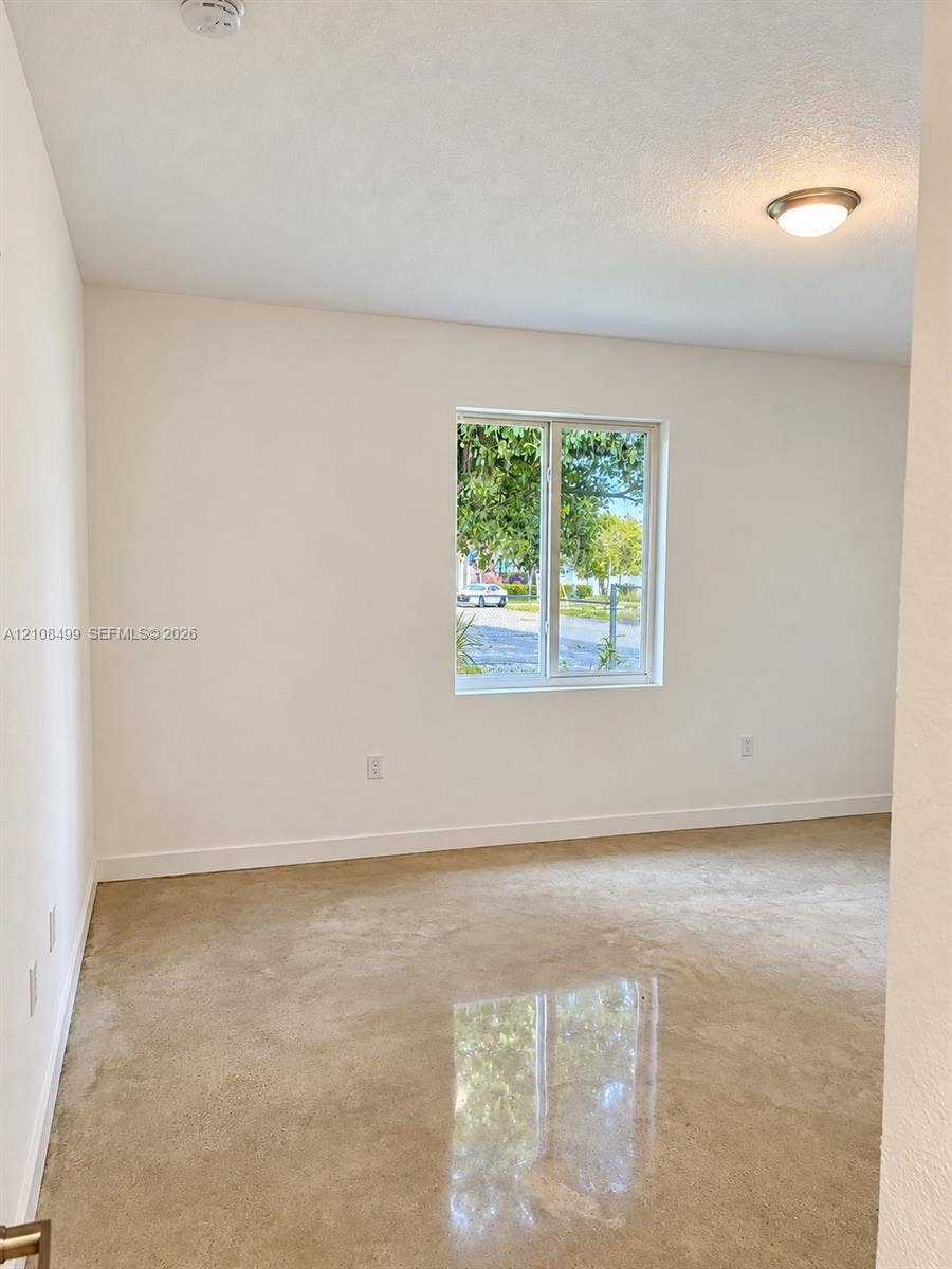104 NW 31st Avenue, Fort Lauderdale, FL 33311 Interior space featuring polished concrete flooring, neutral wall tones, a single-pane window, and a flush-mount ceiling light fixture