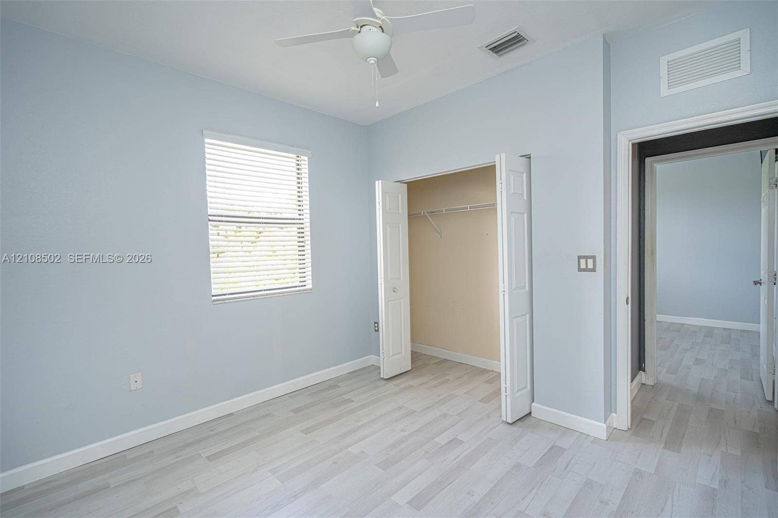 Room featuring wood-finish flooring, a ceiling fan with integrated lighting, and a closet with bifold doors
