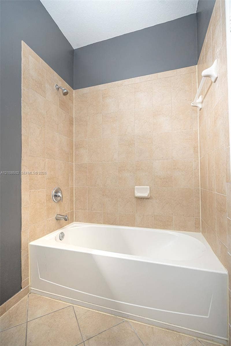 180 NE 26th Avenue, Homestead, FL 33033 Bathtub with a shower head, tiled surround, built-in soap dish, and chrome fixtures