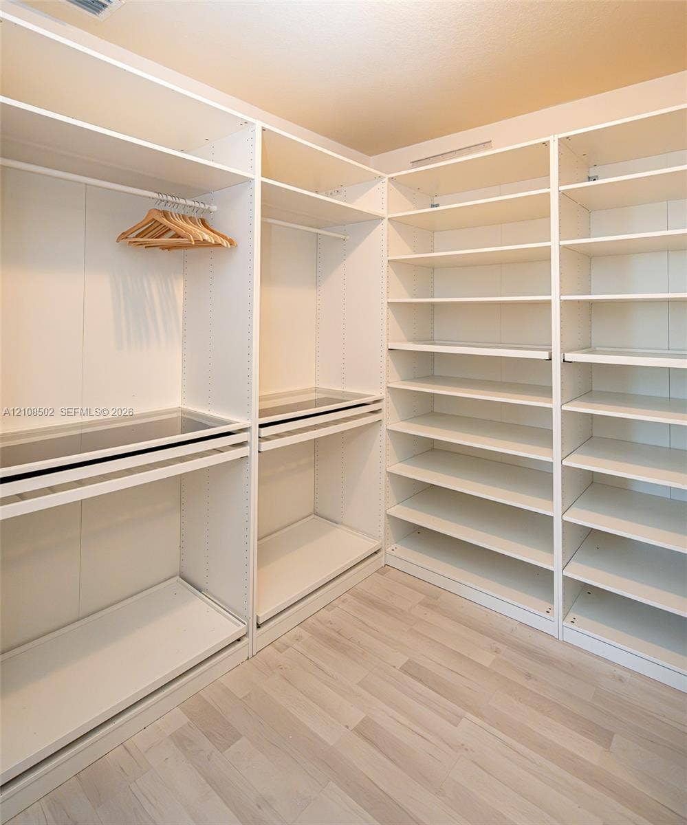 Custom built-in closet organization system featuring adjustable shelving, integrated hanging rods, and wood-finish flooring