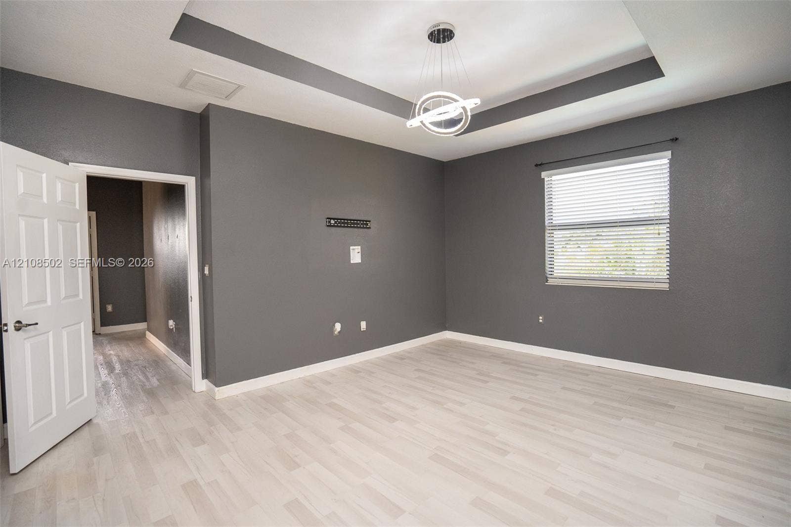 180 NE 26th Avenue, Homestead, FL 33033 Tray ceiling with integrated lighting, wood-finish flooring, and contemporary circular pendant fixture