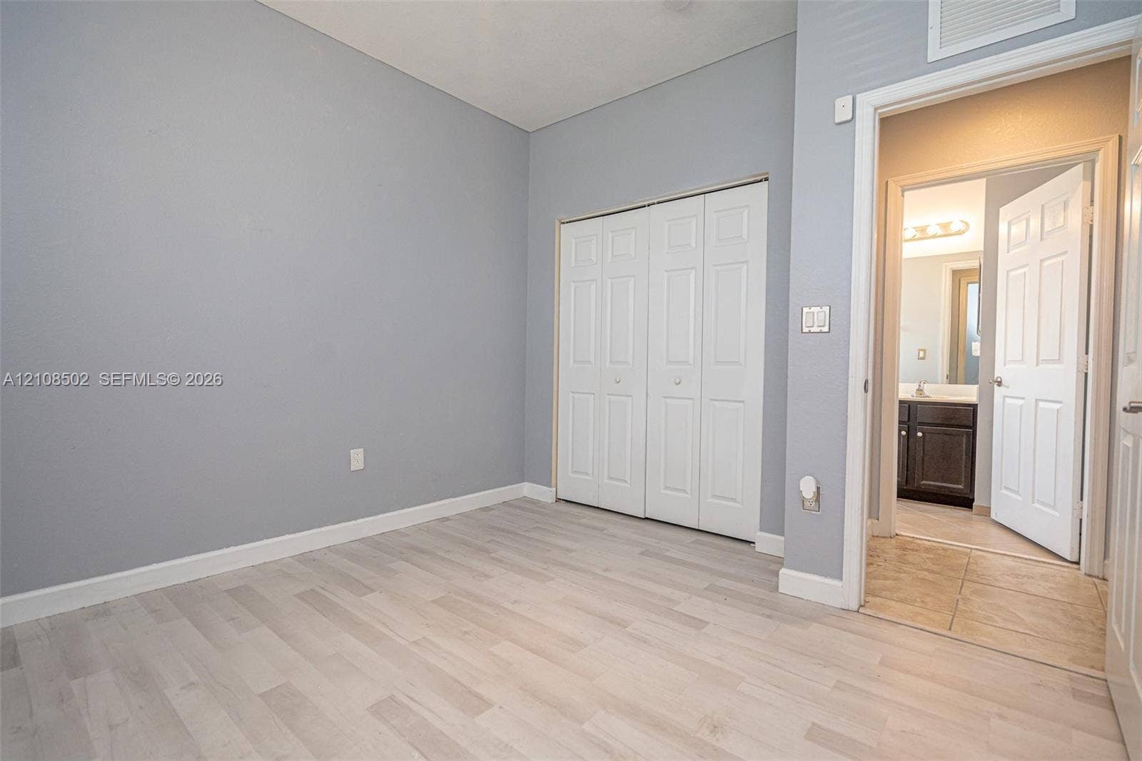 180 NE 26th Avenue, Homestead, FL 33033 Room featuring wood-finish flooring, neutral wall tones, and a double-door closet