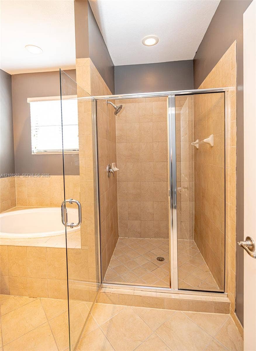 180 NE 26th Avenue, Homestead, FL 33033 Shower enclosure with glass paneling, tile-surround tub deck, neutral wall tiling, and recessed ceiling lighting