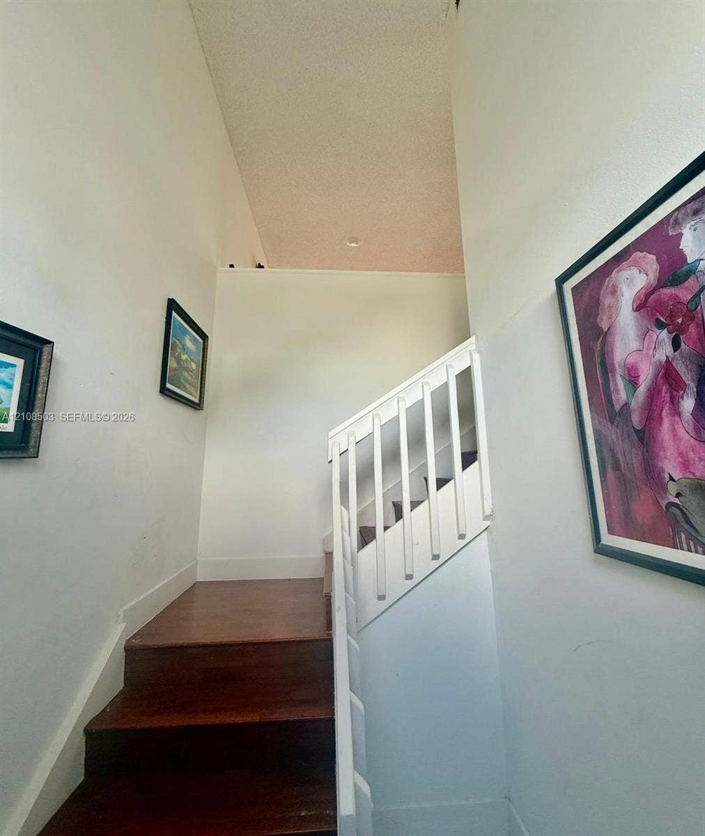 4872 NW 97th Place, #289, Doral, Doral, FL 33178 Staircase featuring wood-finish treads and a white wooden balustrade beneath a vaulted ceiling with recessed lighting