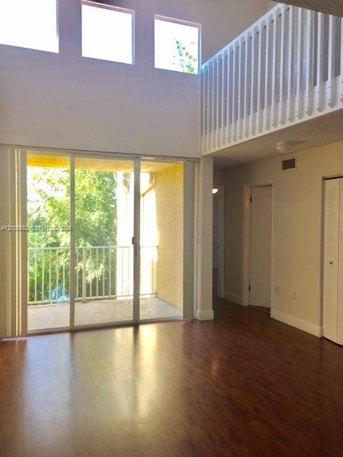 4872 NW 97th Place, #289, Doral, Doral, FL 33178 Double-height living area featuring wood-finish flooring, floor-to-ceiling sliding glass doors, upper-level interior balcony railing, and clerestory windows