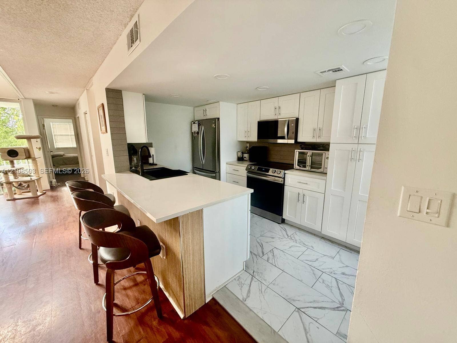 4872 NW 97th Place, #289, Doral, Doral, FL 33178 Kitchen featuring white shaker-style cabinetry, a stone-finish countertop peninsula, stainless steel appliances, and large-format tile flooring