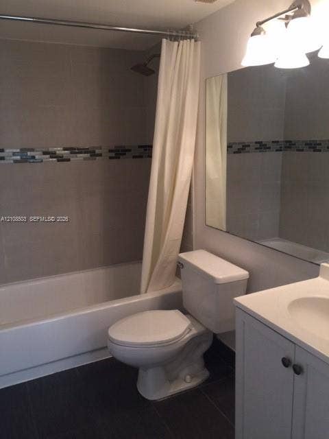 4872 NW 97th Place, #289, Doral, Doral, FL 33178 Bathroom featuring a bathtub with tile surround and decorative glass mosaic inlay, vanity with integrated basin, large wall-mounted mirror, and multi-bulb vanity lighting