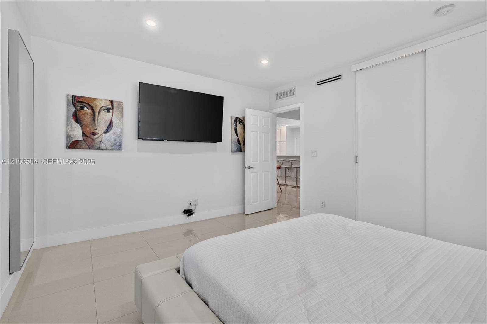 Neutral-toned tile flooring, recessed ceiling lighting, and sliding closet doors with white finish