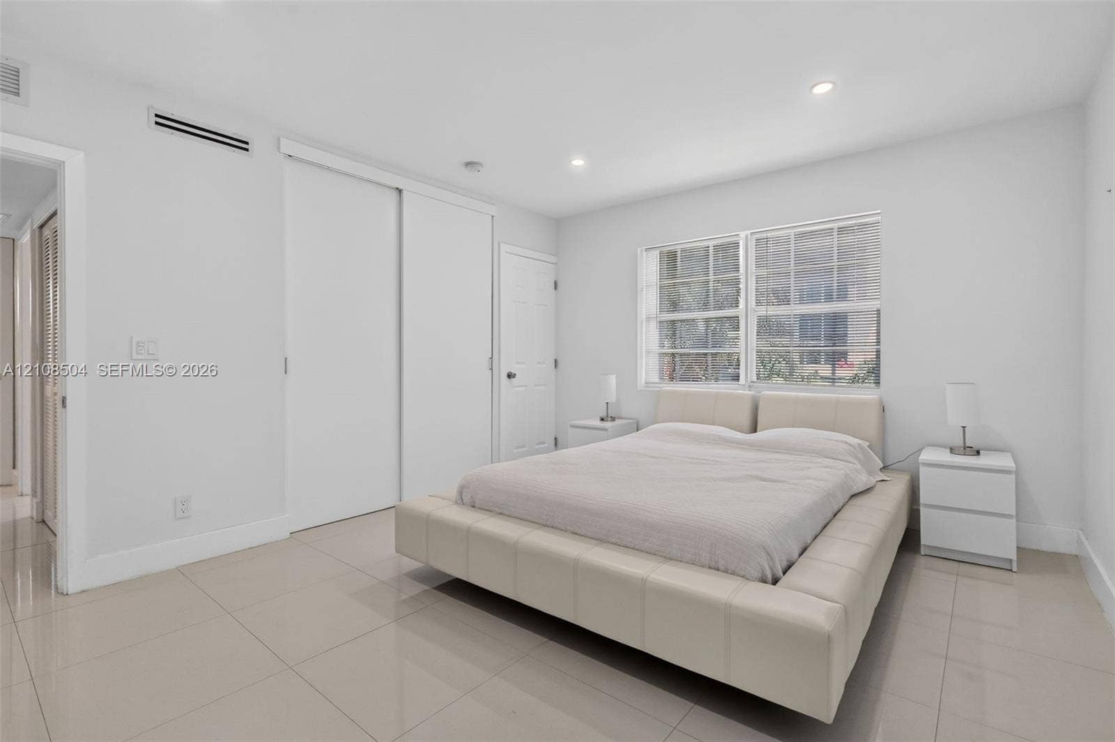 Neutral-toned tile flooring, recessed ceiling lighting, multi-pane windows, and dual sliding closet doors
