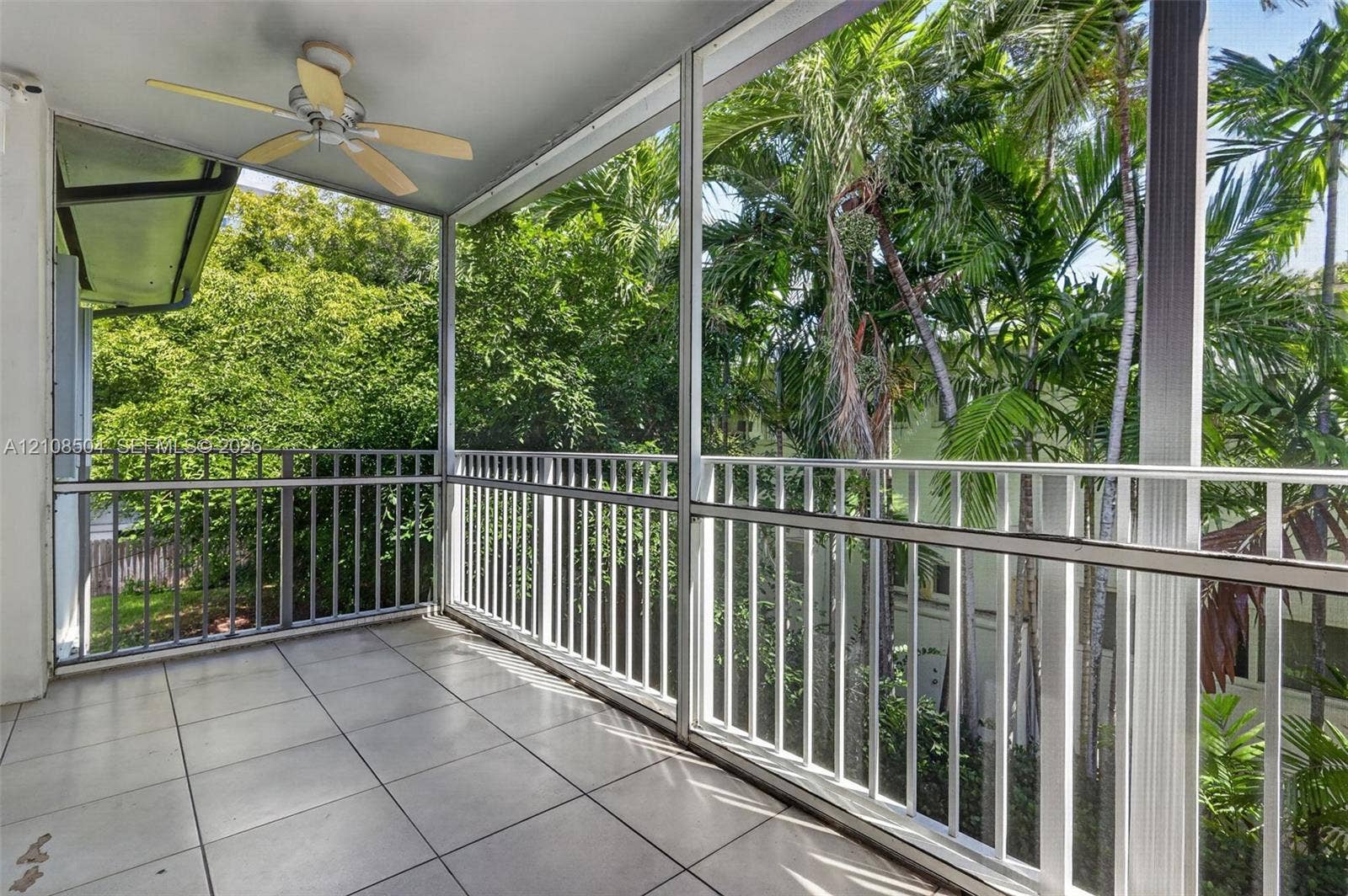 Screened-in balcony featuring tile flooring, white metal railing, and a ceiling fan