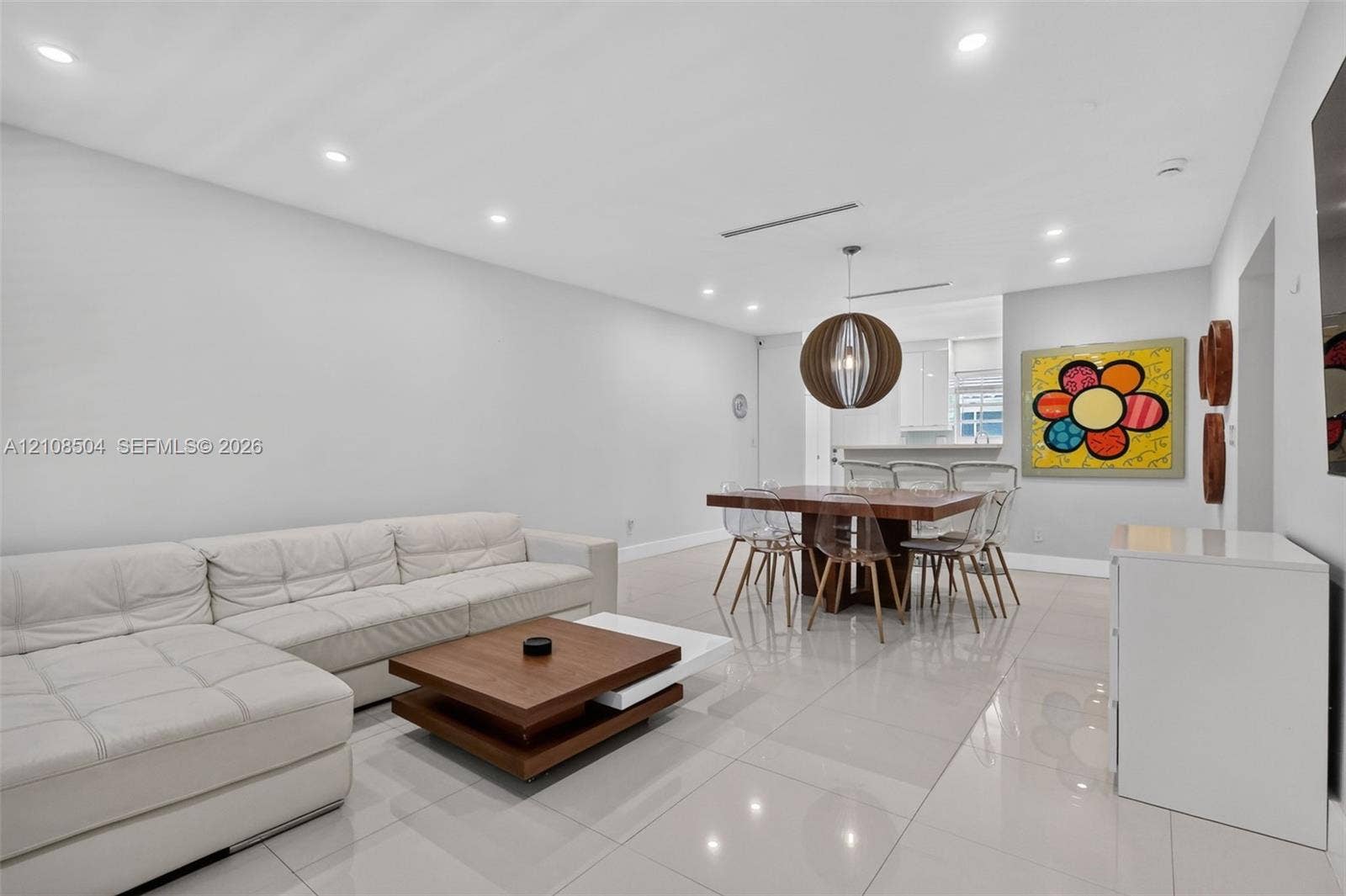 Open-concept interior featuring large-format tile flooring, recessed lighting, and a spherical wood-slat pendant fixture