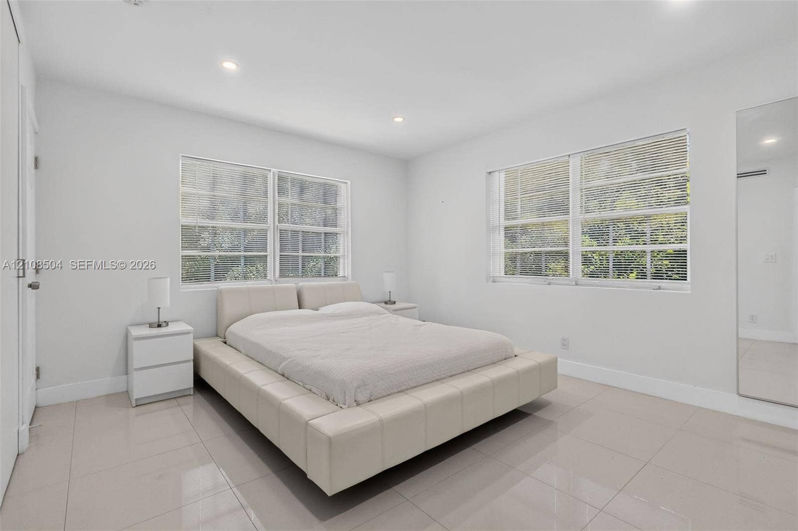 Neutral-toned tile flooring, recessed ceiling lighting, and large dual-pane windows with integrated blinds