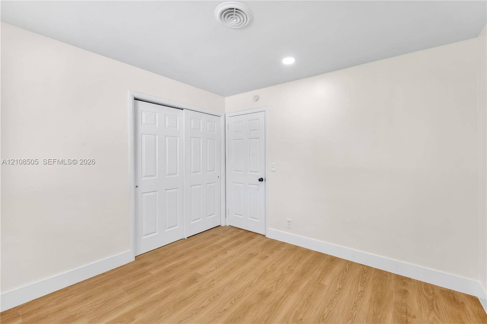 Neutral interior space featuring wood-finish flooring, recessed lighting, and a double-panel sliding closet