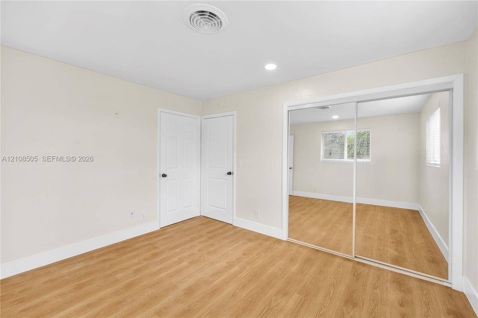 Neutral interior featuring wood-finish flooring, recessed lighting, and a closet with sliding mirrored doors