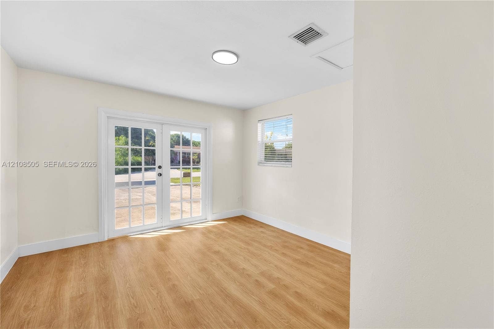 Neutral-toned interior featuring wood-finish flooring, glass-paned double doors, and a recessed ceiling light
