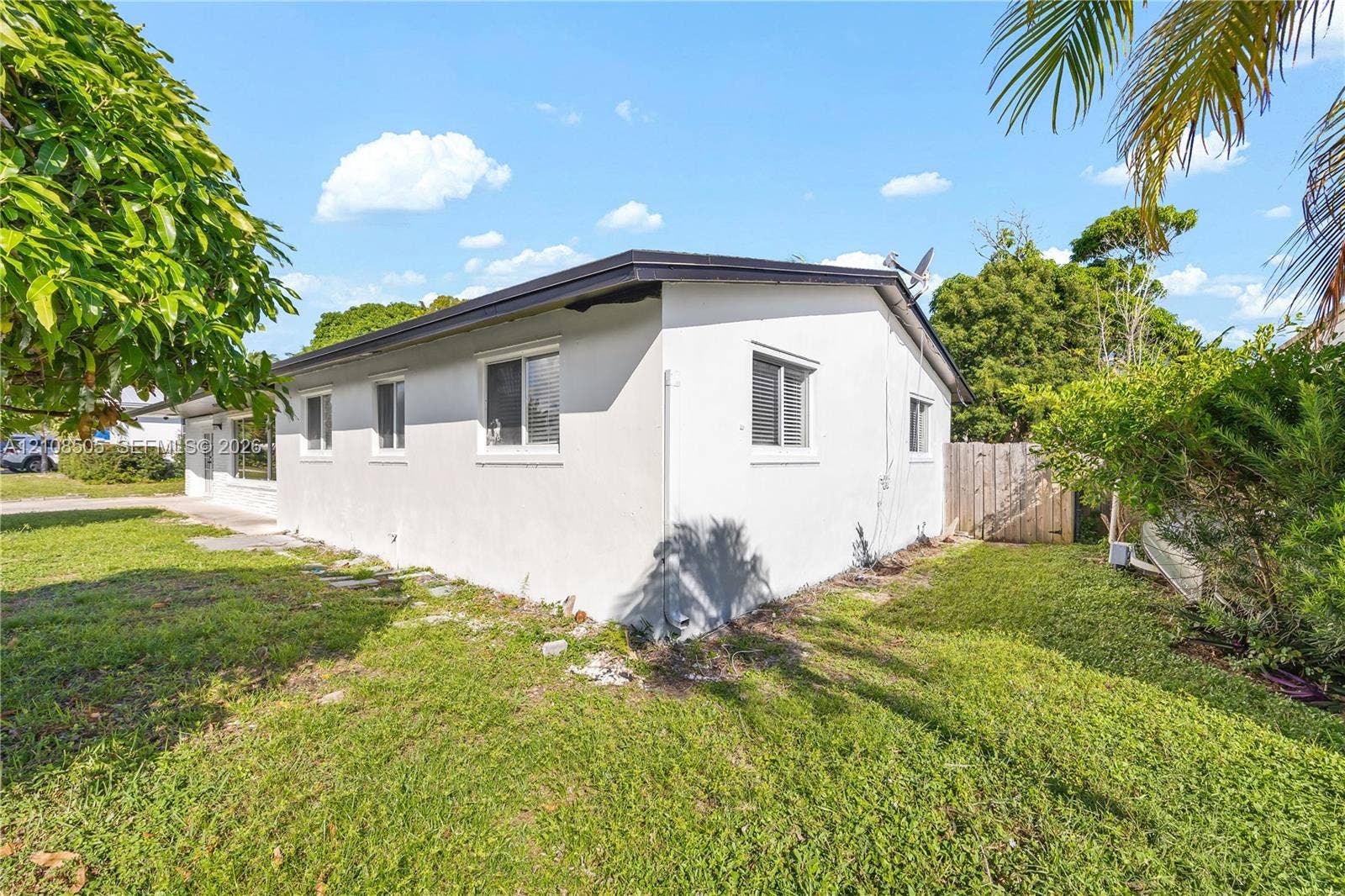 Single-story exterior with stucco siding, horizontal sliding windows, and a wood-slat privacy fence