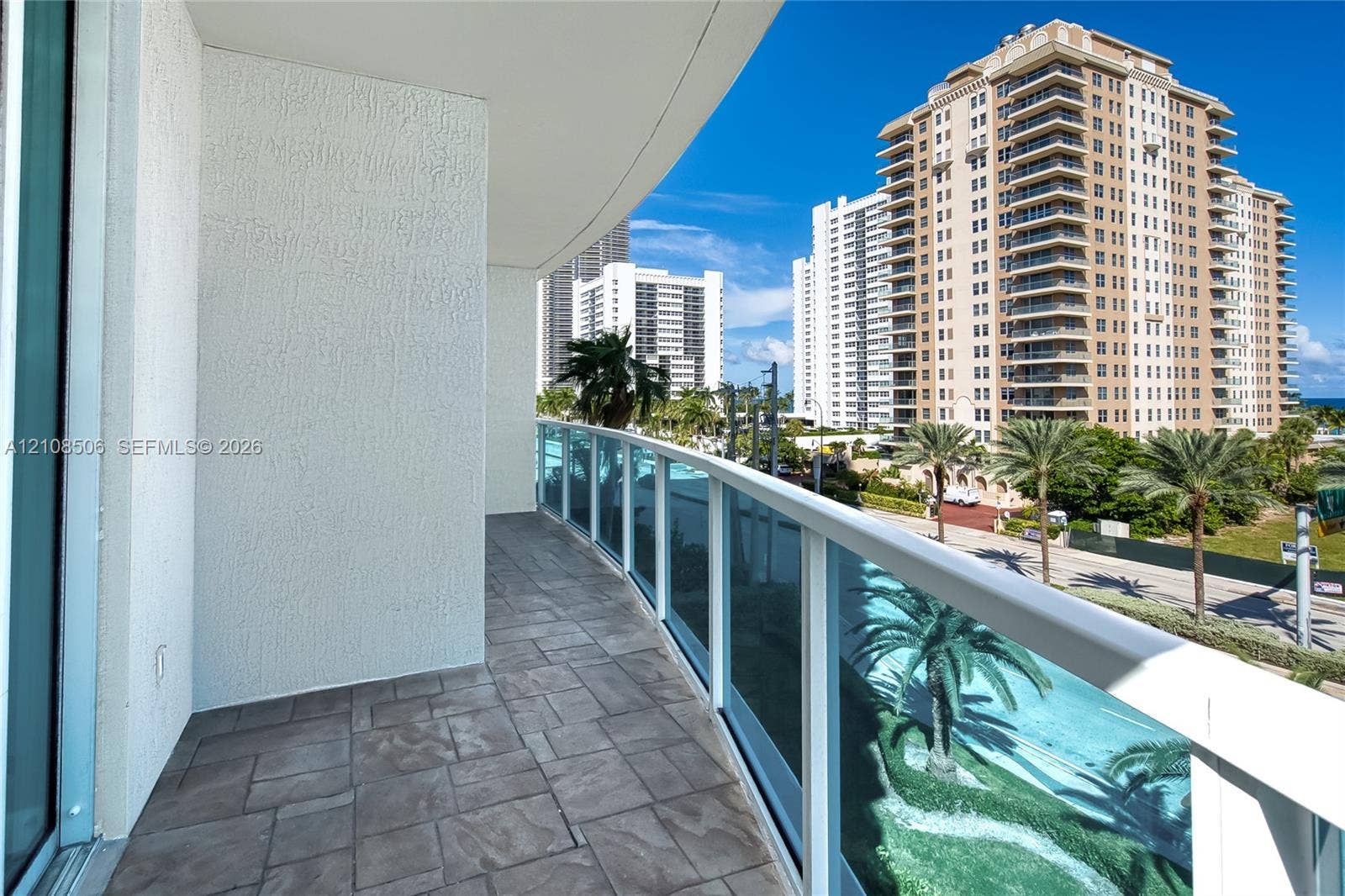 Curved balcony featuring stone-tile flooring and glass panel railings