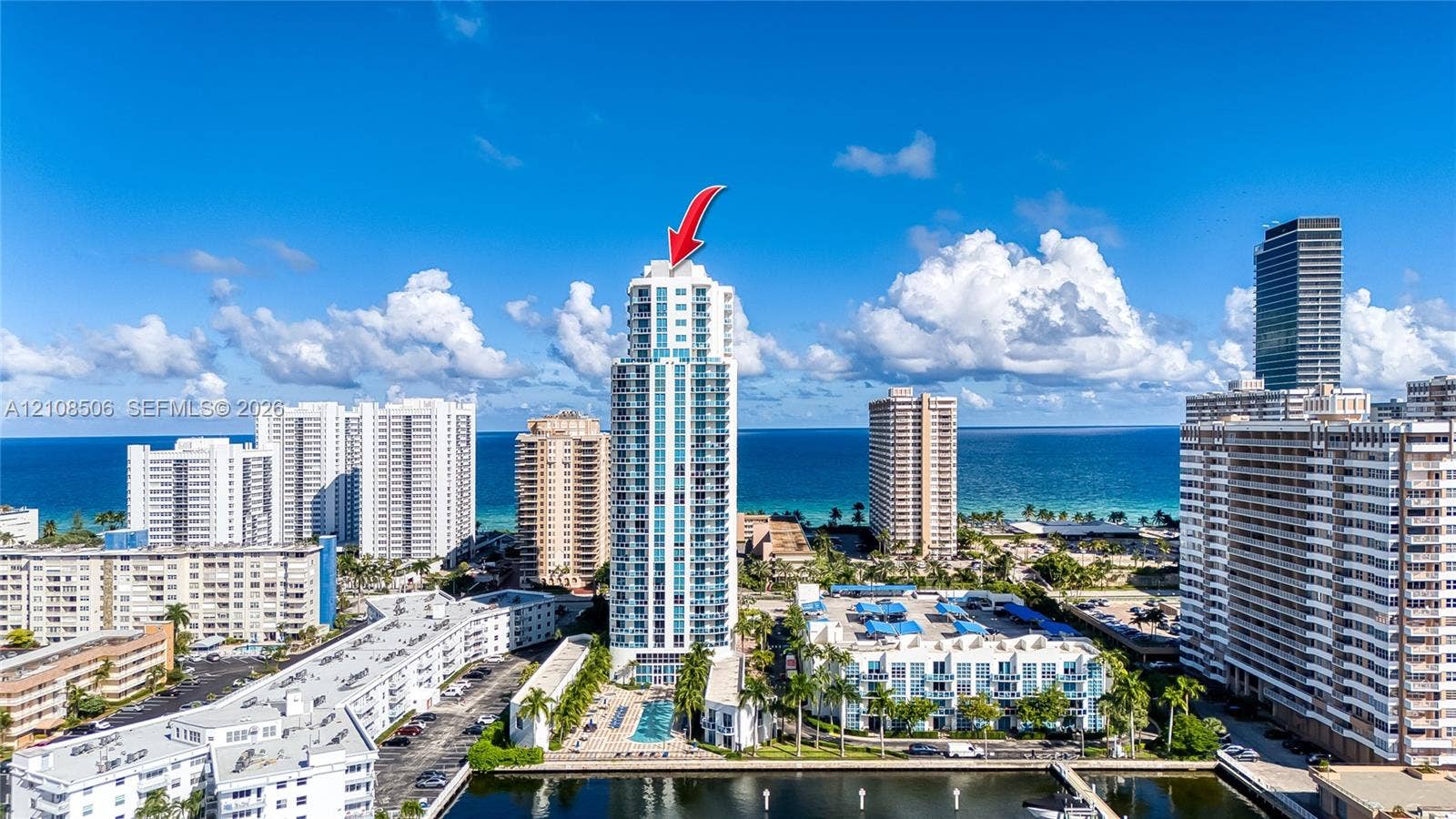 High-rise condominium tower featuring private balconies, integrated glass exterior detailing, and a ground-level swimming pool