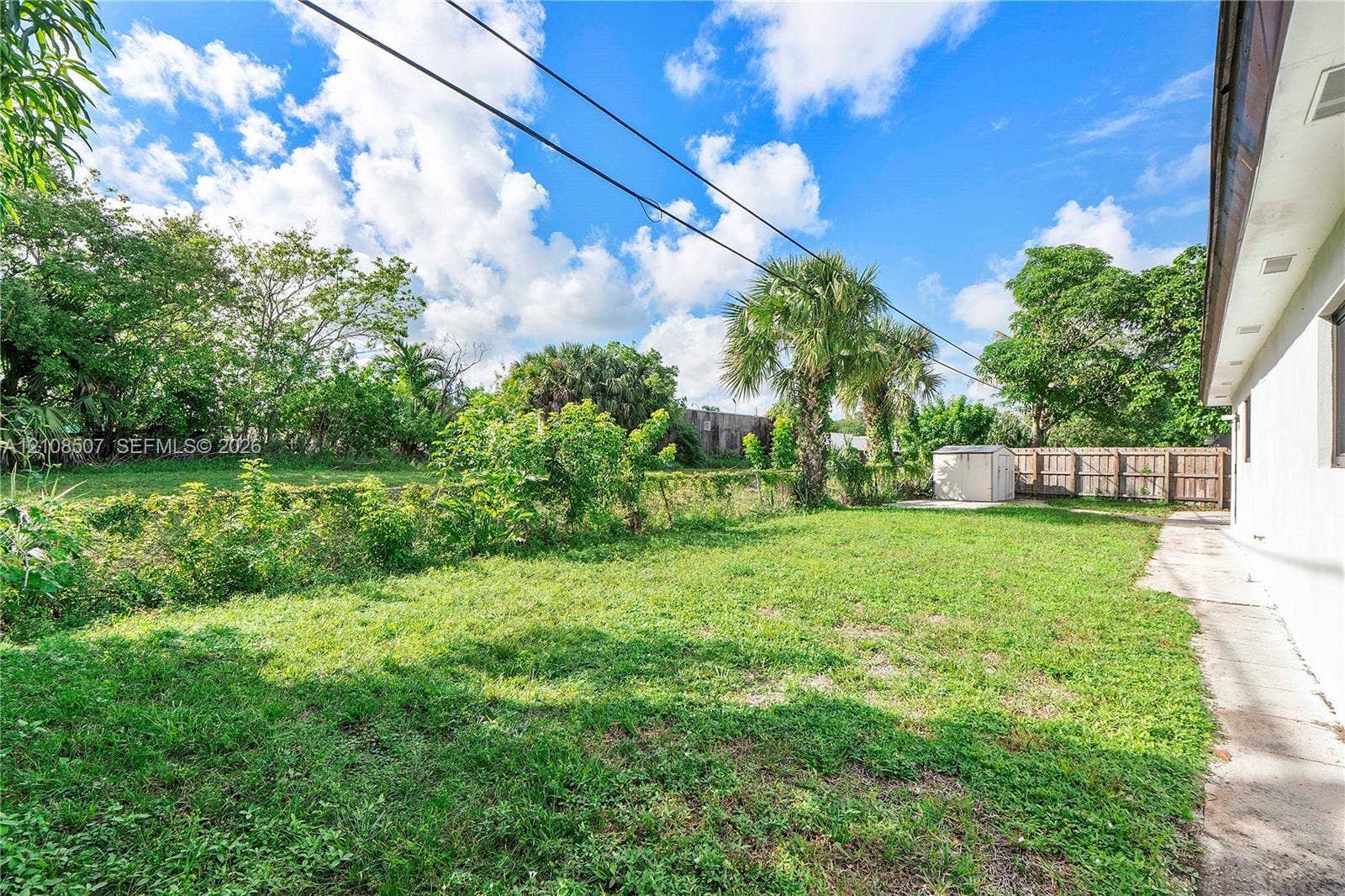 451 SW 38th Terrace, #1, Fort Lauderdale, Fort Lauderdale, FL 33312 Spacious backyard featuring a grass lawn, mature palm trees, perimeter wood fencing, and a detached storage shed