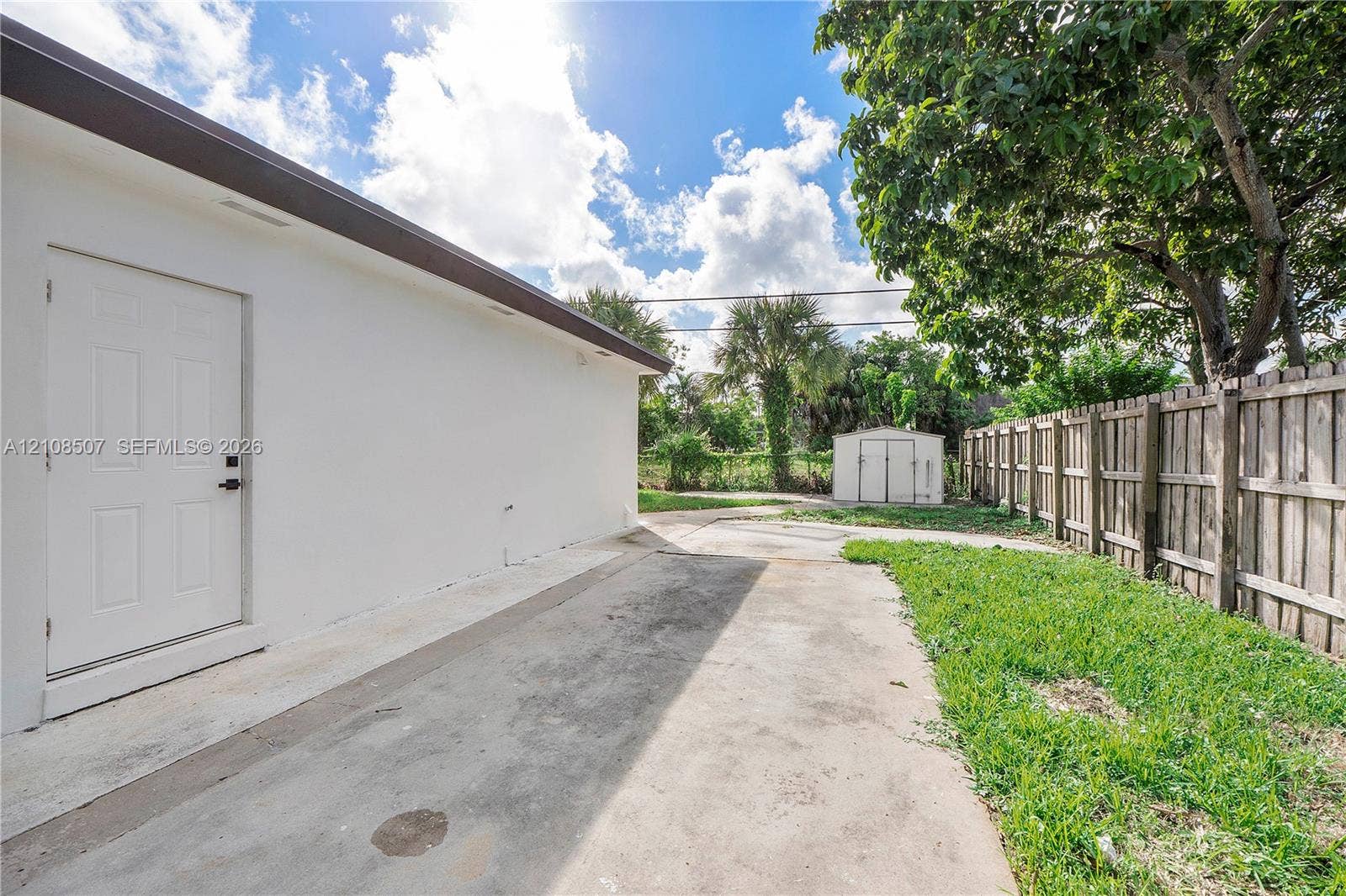 451 SW 38th Terrace, #1, Fort Lauderdale, Fort Lauderdale, FL 33312 Exterior area featuring a concrete side patio, wood-slat privacy fencing, a storage shed, and mature trees
