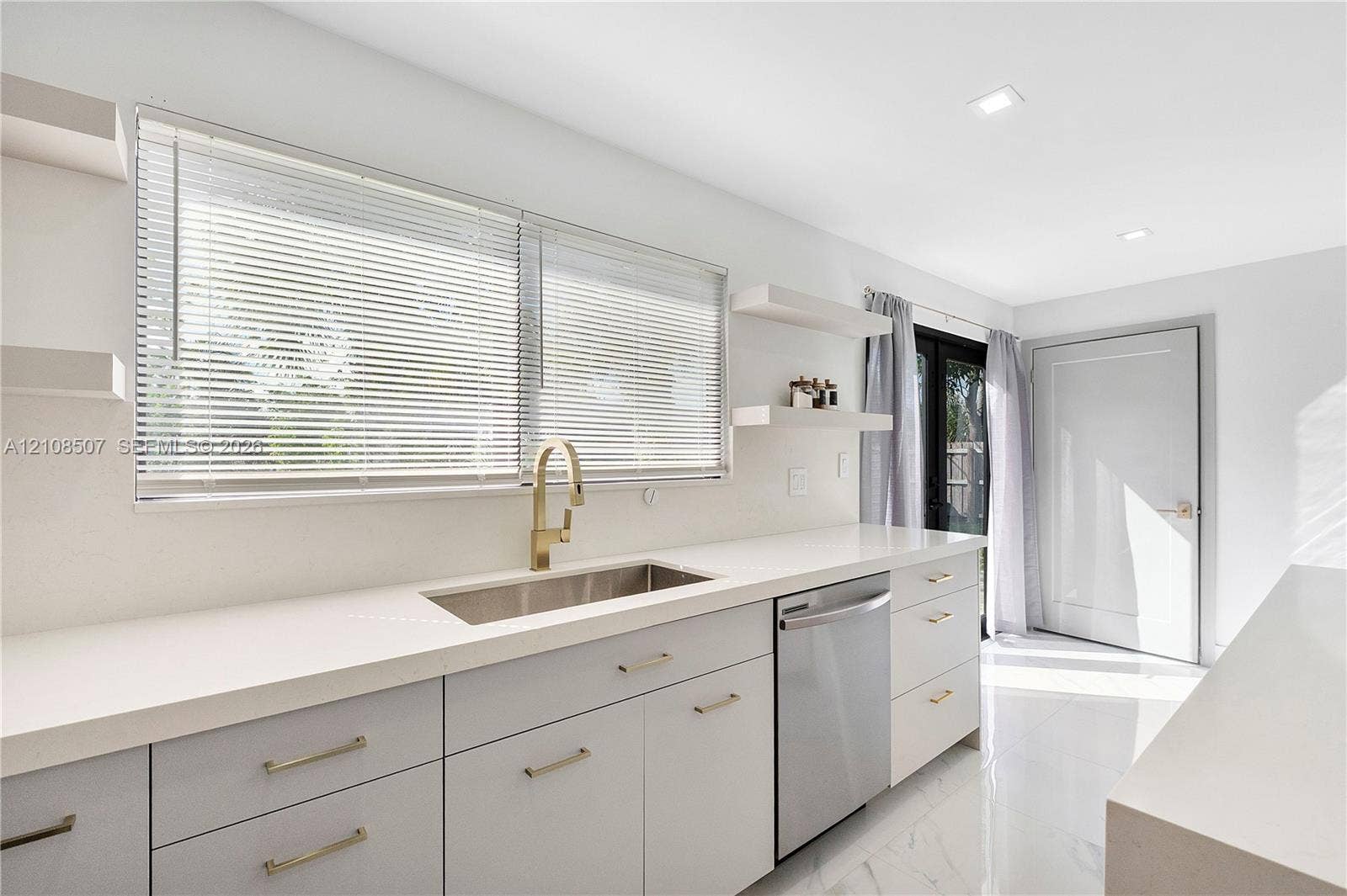 451 SW 38th Terrace, #1, Fort Lauderdale, Fort Lauderdale, FL 33312 Kitchen featuring light-toned cabinetry, solid surface countertops, a stainless steel undermount sink with a brass-finish faucet, built-in stainless steel dishwasher, and wall-mounted shelving