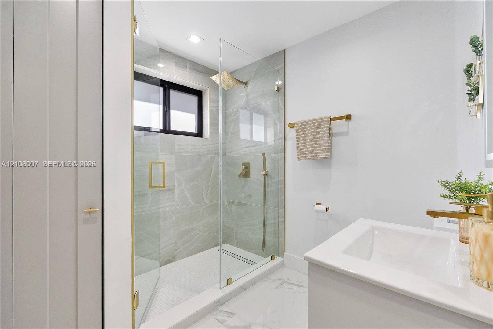 451 SW 38th Terrace, #1, Fort Lauderdale, Fort Lauderdale, FL 33312 Walk-in shower featuring large-format tile surround, glass enclosure, brass-finish fixtures, and a recessed window