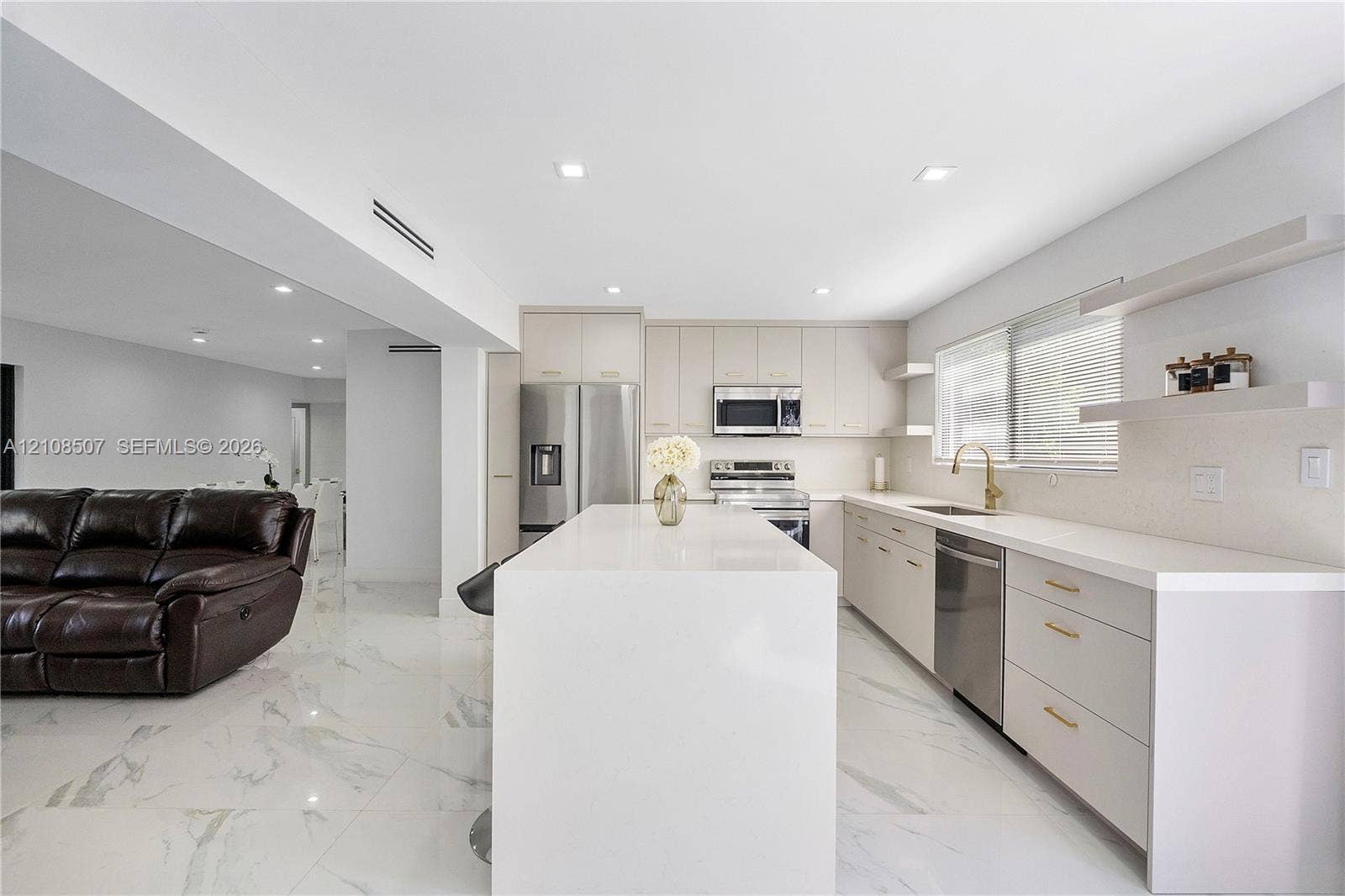 451 SW 38th Terrace, #1, Fort Lauderdale, Fort Lauderdale, FL 33312 Kitchen featuring a stone-finish waterfall island, flat-panel cabinetry, stainless steel appliances, floating wall shelving, and large-format tile flooring