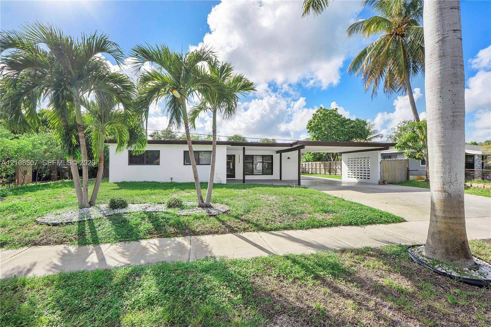 451 SW 38th Terrace, #1, Fort Lauderdale, Fort Lauderdale, FL 33312 Single-story exterior featuring white stucco siding, a covered carport, decorative breezeblock wall accents, and mature palm trees