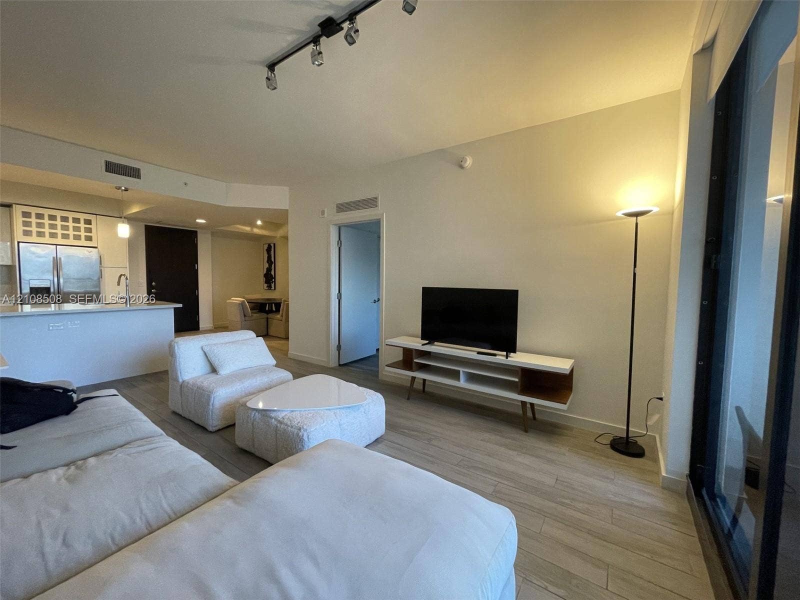 Open-concept floor plan featuring wood-finish flooring, recessed track lighting, and floor-to-ceiling glass paneling