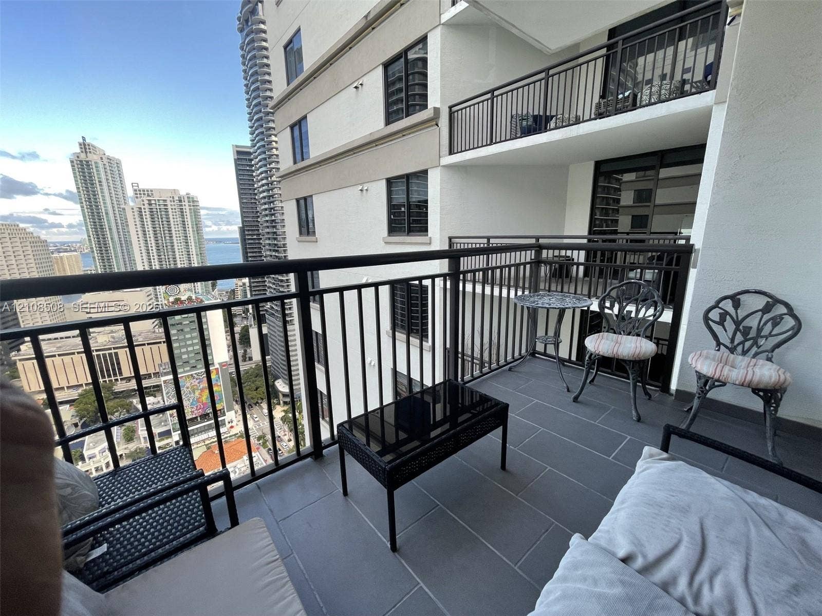 Private balcony featuring dark metal railings, large-format tile flooring, and urban skyscraper surroundings