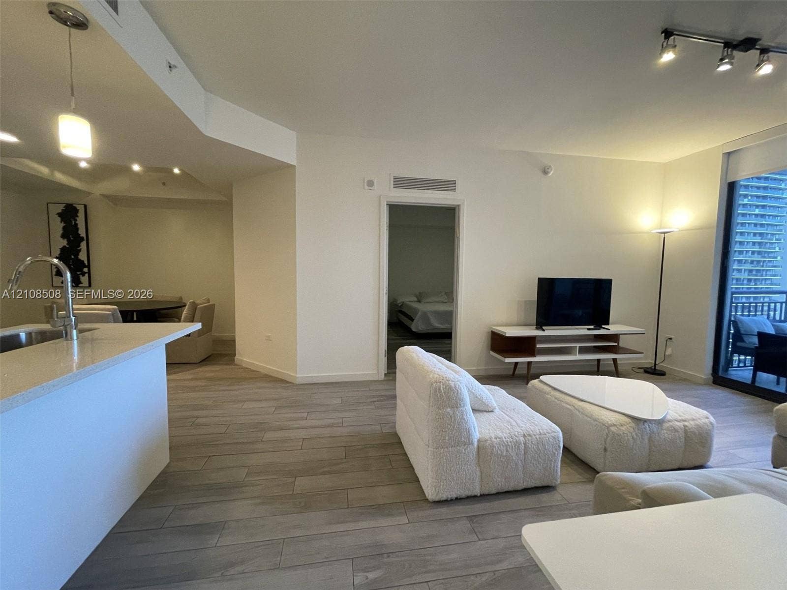 Open-concept interior featuring wood-finish tile flooring, a peninsula with stone countertop, recessed lighting, and floor-to-ceiling glass sliding doors