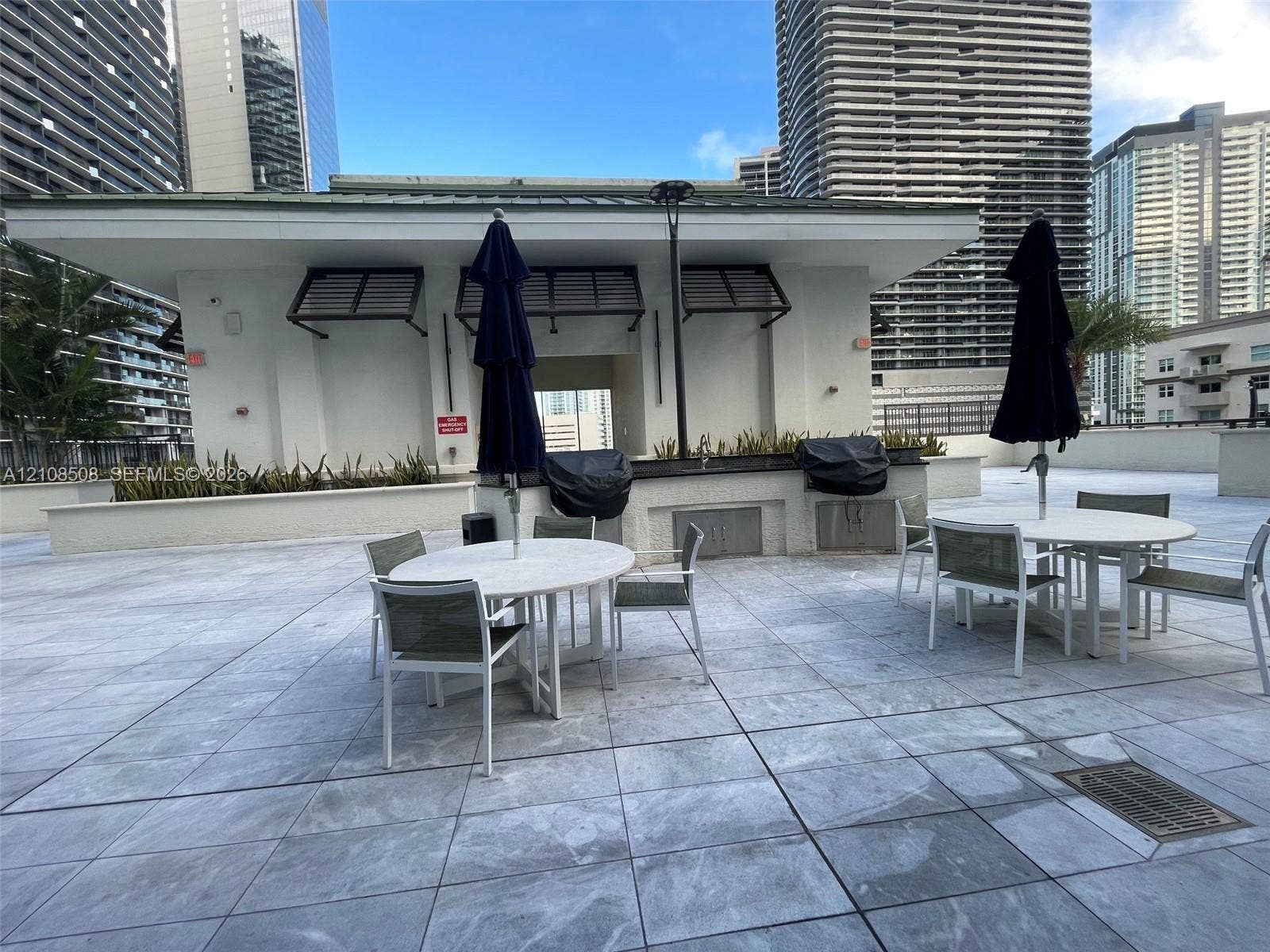Outdoor terrace featuring large-format tile flooring, a covered masonry bar area, and perimeter planter boxes